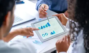 Zespół analizuje dane na tablecie, dyskutując o tym, bik co to za wskaźnik.